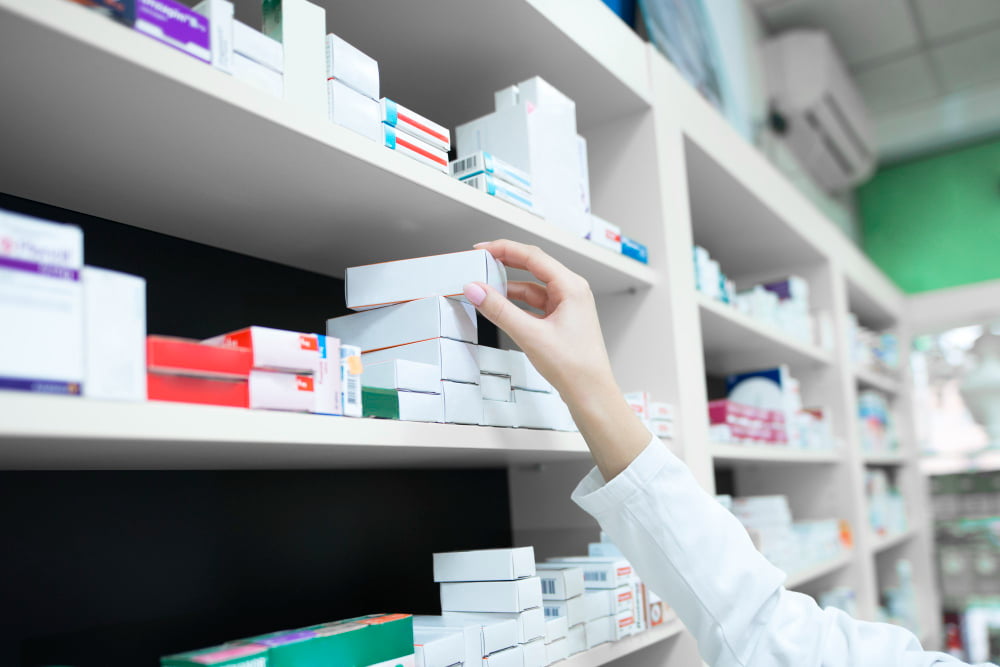 closeup view pharmacist hand taking medicine box from shelf drug store